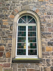 Exterior shot of an ancient Stained Glass Church window with old Stone Wall surrounding it
