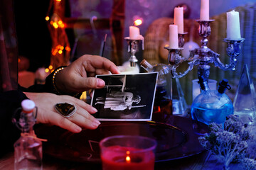 spiritualistic seance in salon of medium with old photographs of deceased relatives, Female Fortuneteller or esoteric Oracle, longing for ancestors, communication with world spirits, help of ancestors - obrazy, fototapety, plakaty