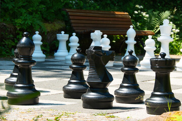 Ein großes Schachspiel in einem öffentlichen Park, mit einer hölzernen Sitzbank im Hintergrund © joerghartmannphoto