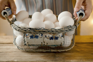 mesh vintage metal basket with fresh white chicken eggs on wooden table, valuable food product,...