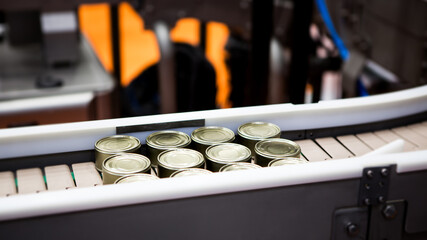 Food canned factory. Food tin cans on belt conveyor. Food industry.