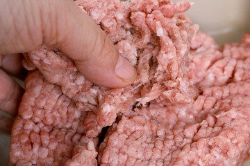 closeup female hand kneads minced meat, raw fresh minced meat with fat from pork, beef, lamb,...