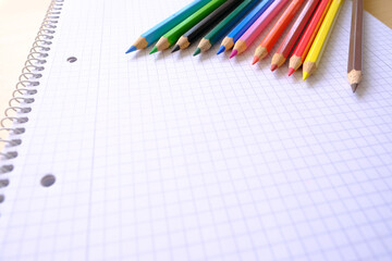 school background, colored pencils lie on a sheet of paper, an open notebook on a spiral, a college...