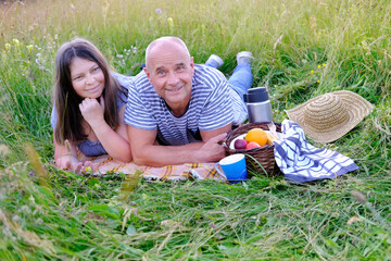 mature man 60 years old, woman 50 years old in blue clothes lie on grass in meadow, next to picnic...