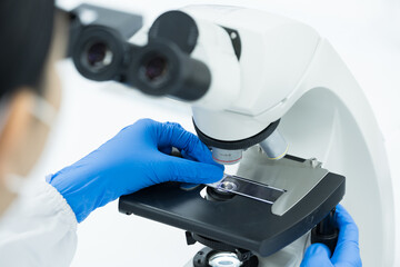 Women scientist looking to microscope eyepiece in clinical laboratory.Young scientist doing some...