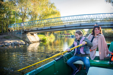 In the park, a girl with her mother is sailing on a boat.