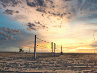 Volleyball net on empty beach under sunrise sky