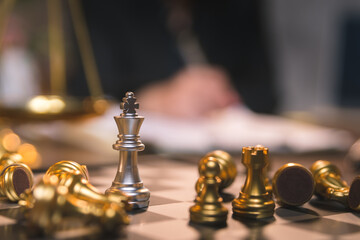Silver chess king standing among golden falling chess pieces, business competition has winners and losers, strategy will make company successful, investment and management concept.