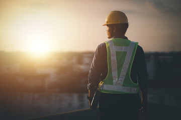 Engineer on a construction site at sunset. Working on the roof . - 614470483