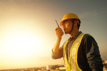 Engineer using walkie talkie and talking about work construction site. talking by walkie talkie control and communicate with worker. Contractor man using radio operation in industry. - 614470494