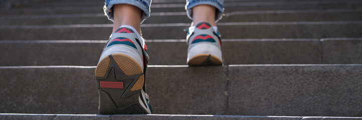 Fototapeta na wymiar Closup of woman legs in sneakers walking up steps