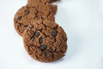 heap of brown cookies with choco chips on white background, delecious and crumbs snack