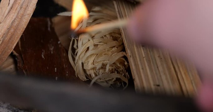make a fire in a wood stove. light a fire with a match. burn a fire starter. wood wool to start a fire. burning match in a fireplace