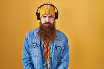 Caucasian man with long beard listening to music using headphones depressed and worry for distress, crying angry and afraid. sad expression.