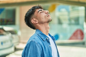 Young hispanic man breathing with closed eyes at street