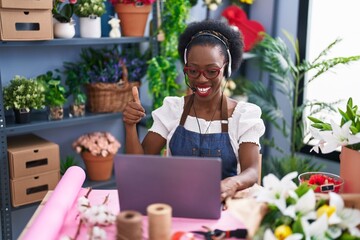 African woman with curly hair working at florist shop doing video call smiling happy and positive, thumb up doing excellent and approval sign