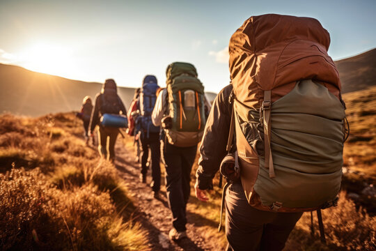 A close - up photo of a group of hiker tourists walking along a mountain ridge at sunset. Generative AI