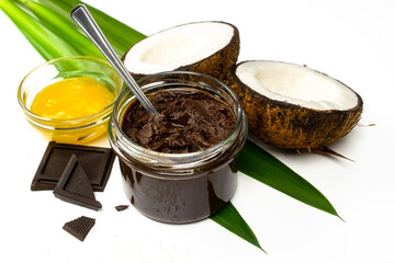 Coconut halves, chocolate paste and honey on white background. Homemade carob butter with ingredients. Healthy sweet food concept