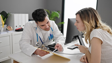 Man and woman doctor and patient having consultation showing medical report at clinic