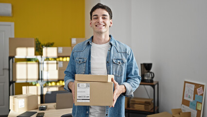 Young hispanic man ecommerce business worker holding packages at office