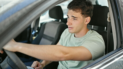 Young hispanic man driving car at street