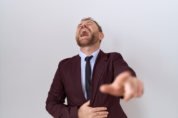 Middle age business man with beard wearing suit and tie laughing at you, pointing finger to the camera with hand over body, shame expression - obrazy, fototapety, plakaty