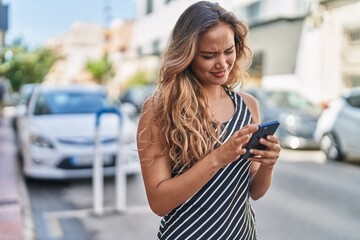 Young beautiful hispanic woman smiling confident using smartphone at street