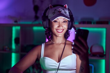 Young beautiful hispanic woman streamer smiling confident using smartphone at gaming room © Krakenimages.com