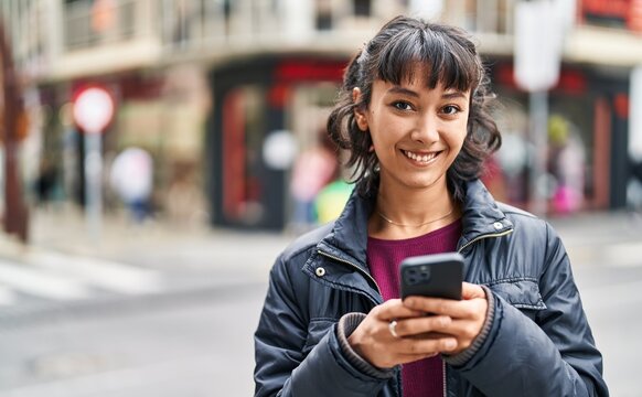 Young beautiful hispanic woman smiling confident using smartphone at street