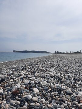 Image of deep blue sea and cloudy sky and pebbles