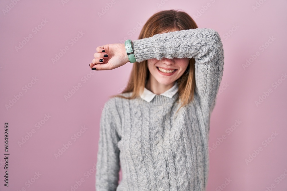 Sticker beautiful woman standing over pink background covering eyes with arm smiling cheerful and funny. bli