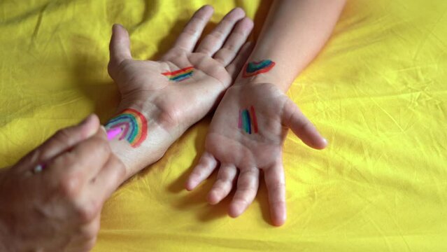 DA FARE 1hands of father and 9 boy kid with LGBT flag rainbow symbol of homosexual gay couple rights. Union between same-sex couples and recognition son  -  Gay pride manifestation adopted  rights
