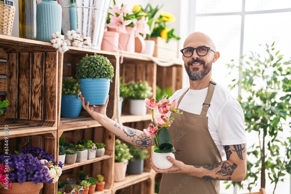 Sticker Young bald man florist smiling confident holding plants at florist