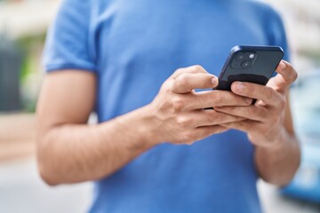 Young latin man using smartphone at street