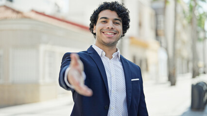 Young latin man business worker smiling confident shake hand at street