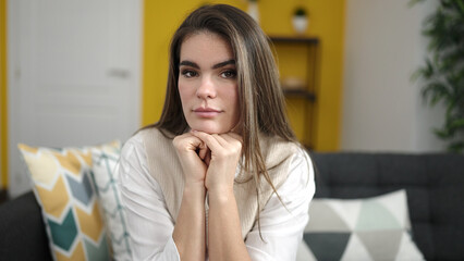 Fototapeta na wymiar Young beautiful hispanic woman sitting on sofa with serious expression at home