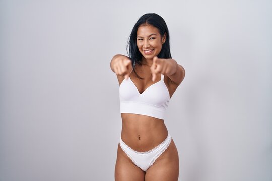 Hispanic woman wearing lingerie pointing to you and the camera with fingers, smiling positive and cheerful