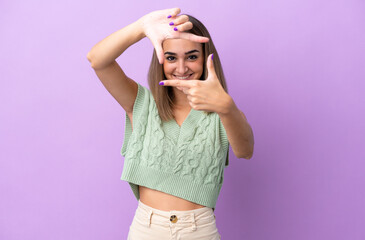 Young caucasian woman isolated on purple background focusing face. Framing symbol