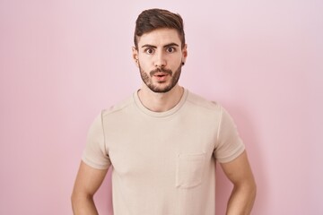 Fototapeta premium Hispanic man with beard standing over pink background afraid and shocked with surprise and amazed expression, fear and excited face.