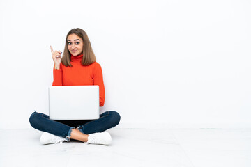 Young caucasian woman sitting on the floor with a laptop pointing with the index finger a great idea