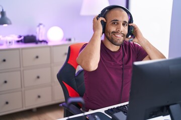 Young latin man streamer smiling confident sitting on table at gaming room