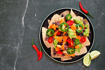 Fully loaded nachos with beef and cheese. Mexican food dish. Above  view on a dark slate background.
