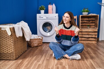 Young hispanic girl doing laundry very happy and excited doing winner gesture with arms raised, smiling and screaming for success. celebration concept.