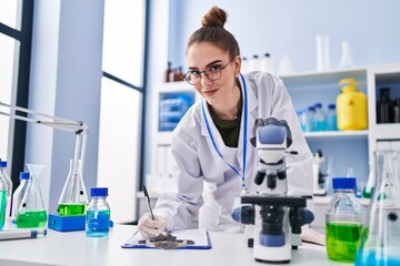 Young woman scientist writing on clipboard at laboratory