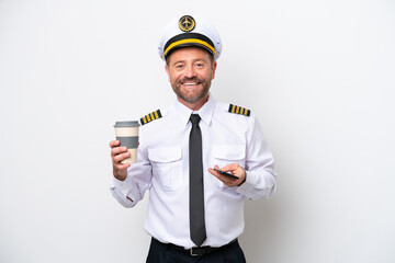 Airplane middle age pilot isolated on white background holding coffee to take away and a mobile