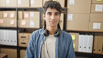 Young hispanic man ecommerce business worker sitting on table smiling at office