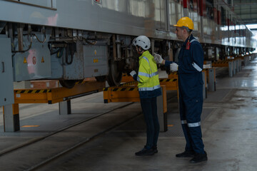 The technicians together with the engineers inspect the structure of the train propulsion system to maintain the trains in the depot.