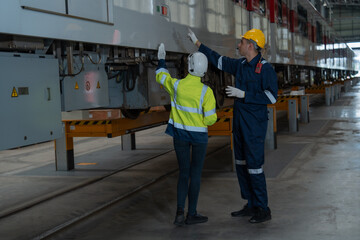 The technicians together with the engineers inspect the structure of the train propulsion system to maintain the trains in the depot.