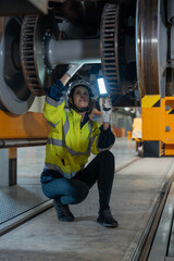 Fototapeta premium Female engineer inspecting electric train repair and maintenance in maintenance station