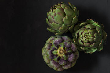 Fototapeta premium Fresh ripe artichokes flowers vegetable on black background. Healthy vegetarian food. top view with copy space